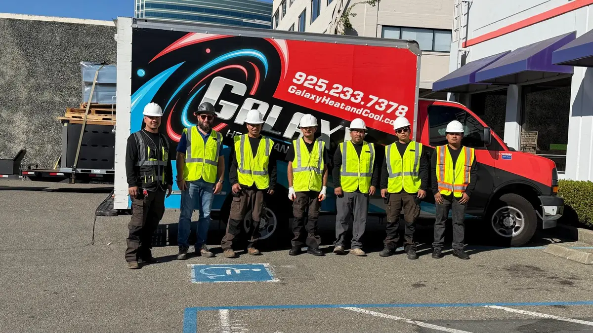 Galaxy commercial HVAC team wearing hard hats and safety vests beside their service truck at a job site