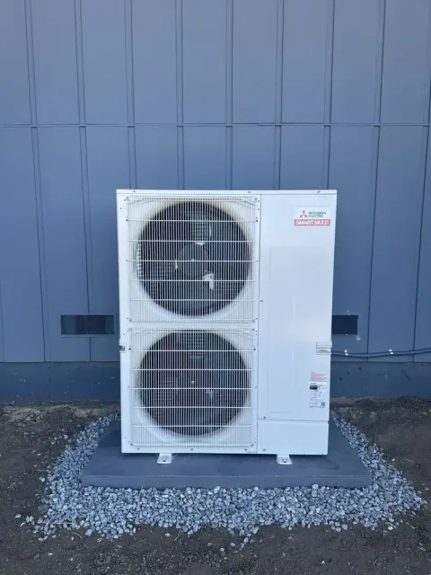 Mitsubishi Electric dual-fan outdoor unit mounted beside blue exterior siding in Orinda