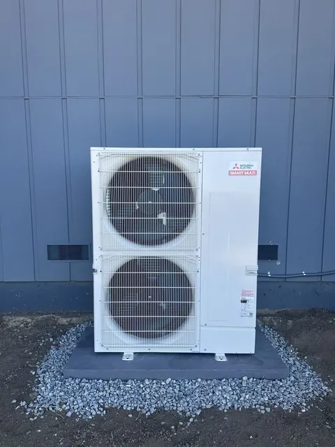 Mitsubishi Electric dual-fan outdoor unit mounted beside blue exterior siding in Orinda