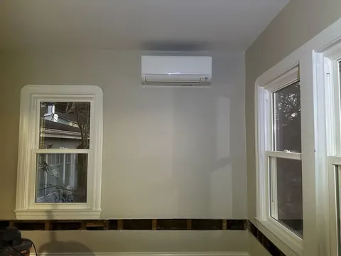 White wall-mounted mini-split indoor unit positioned above a window in a room under renovation in Hayward