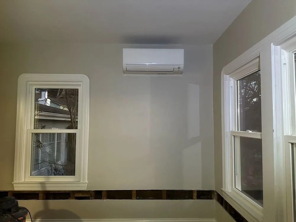 White wall-mounted mini-split indoor unit positioned above a window in a room under renovation in Hayward