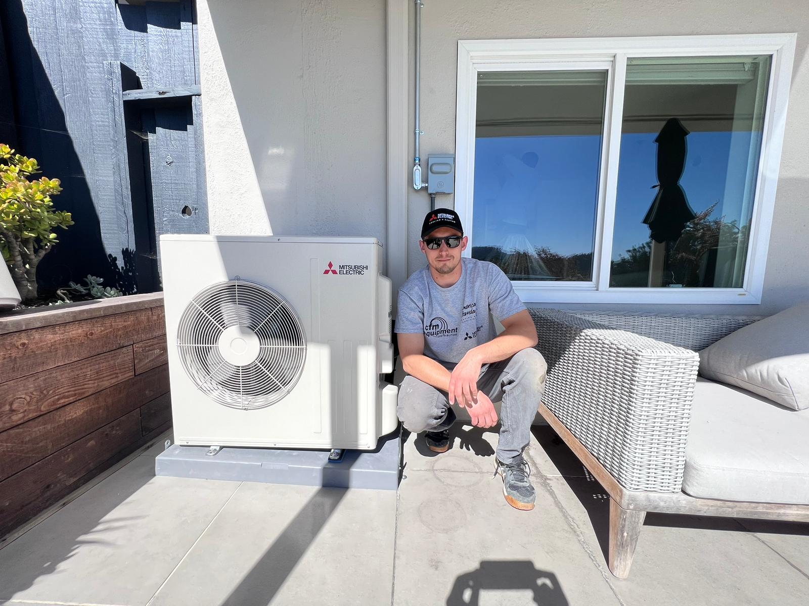 Galaxy Heating & Air technician with a newly installed Mitsubishi ductless heat pump outdoor unit at a Victoria by the Bay Hercules home