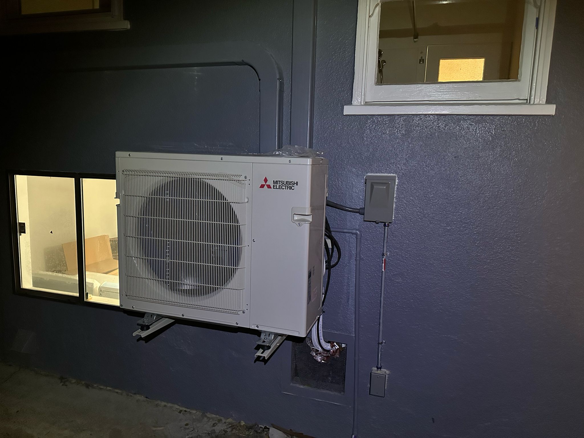 Mitsubishi Electric ductless heat pump outdoor unit on wall-mounted bracket installed by Galaxy Heating & Air at an Allied Arts Menlo Park home