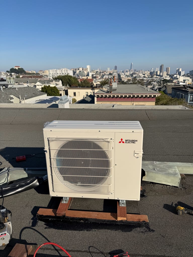 Mitsubishi heat pump installed by Galaxy Heating & Air on a San Francisco rooftop with city skyline views