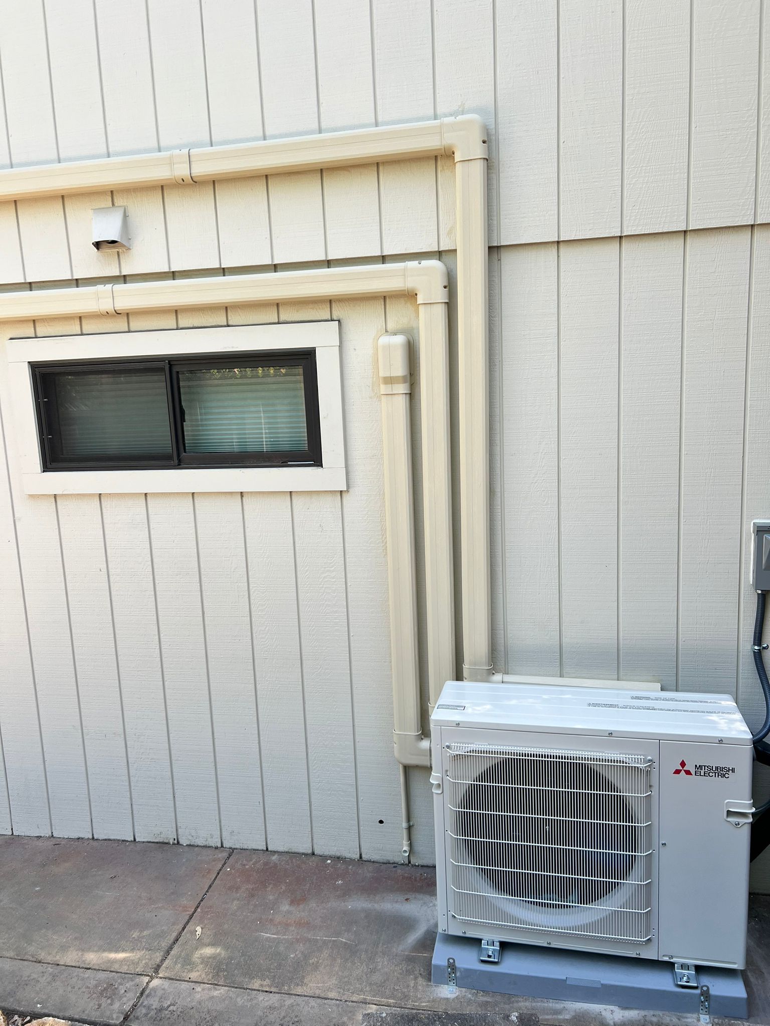 Mitsubishi 3-zone ductless heat pump outdoor unit with painted line-set cover installed by Galaxy Heating & Air at a Walnut Creek home